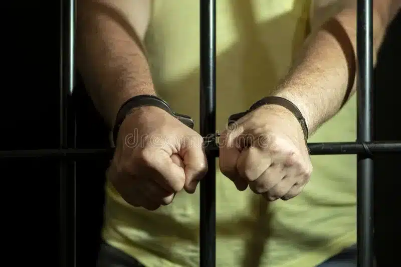 A Man in Handcuffs in a Cell Behind Bars. Concept: a Prisoner in a ...