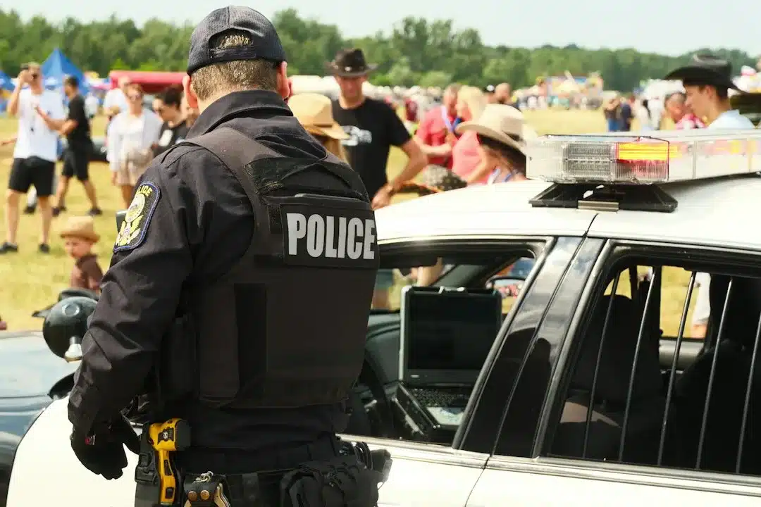 Police officer stands by patrol car at outdoor event